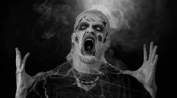 僵尸男子化妆假伤口疤痕和白色隐形眼镜看着相机 点击他的牙齿 试图吓唬在黑暗的房间 Sinister死的家伙 万圣节 舞台的概念 — 图库照片