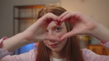 I love you. Teen child girl makes symbol of love, showing heart sign to camera, express romantic feelings, express sincere positive feelings. Charity, gratitude, donation. Children close-up happy face