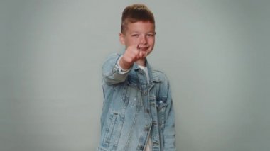I choose you. Toddler boy pointing to camera and looking with playful happy expression, making choice, showing direction. Young one teenager children. Child kid isolated on gray studio background