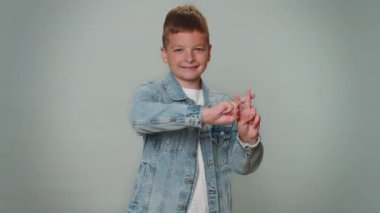 Cheerful toddler kid boy showing hashtag symbol with hands, likes tagged message, popular viral content, sign to follow internet online trends. Young teenager child schoolboy on gray studio background