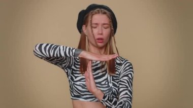 Time out, need a break. Tired serious upset pretty young woman in crop top showing pause relax gesture, limit or stop sign. Adult stylish female girl isolated alone on beige studio background indoors