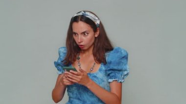 Sad young woman in blue princess dress use smartphone typing browsing, loses becoming surprised sudden lottery results, bad fortune, loss. Adult stylish girl isolated on gray studio background indoors