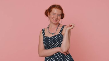 Siyah elbiseli neşeli kızıl saçlı genç kadın gülümsüyor, kameraya bakıyor, flört ediyor. Pembe arka planda izole edilmiş, kapalı mekânlarda çekilmiş kızıl saçlı bir kız. Kadın doğası güzelliği