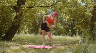 Spor yapan genç bir kadın spor yapıyor. Parkta egzersiz yapıyor. Güneşli bir günde zayıf atletik kız antrenmanı. Spor giyim eğitiminde aktif bayan sporcu kadın. Sağlıklı yaşam tarzı