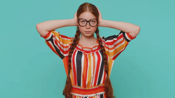 Dont want to hear and listen. Frustrated annoyed irritated redhead girl covering ears and gesturing no, avoiding advice ignoring unpleasant noise loud voices. Young ginger child kid on blue background