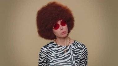 Surprised comical playful woman making fish grimace pout lips, smooching choking, looking with shocked dumb idiotic expression, doing duck face, fooling around. Adult stylish funny girl on beige wall