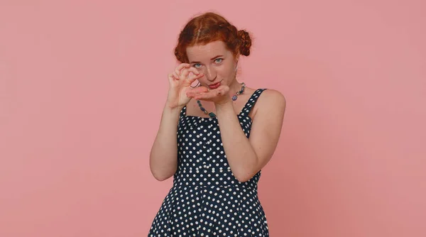 Need some more please give me. Woman showing a little bit gesture with sceptic smile, showing minimum sign, measuring small size asking for help. Ginger girl isolated alone on pink studio background