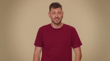 You are crazy, out of mind. Bearded handsome young man pointing at camera and showing stupid gesture, blaming some idiot for insane plan. Adult stylish guy isolated on beige studio background indoors