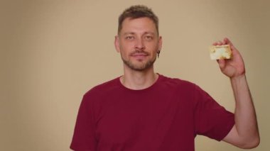 Happy man showing plastic credit bank card advertising transferring money cashless, purchases online shopping, sale discount, internet order delivery purchase. Adult stylish guy on beige background