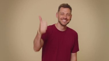 Like. Bearded handsome young man raises thumbs up agrees with something or gives positive reply recommends advertisement likes good. Adult stylish guy isolated alone on beige studio background indoors