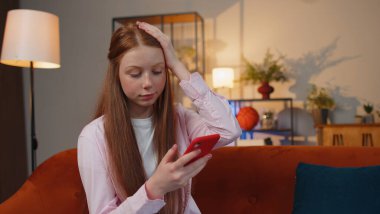 Genç kızıl saçlı genç kız akıllı telefon daktilo kullanıyor. Ani piyango sonuçlarını kaybediyor. Kötü haber, servet kaybı, başarısızlık. Oturma odasındaki kanepede oturan kızıl saçlı çocuk.