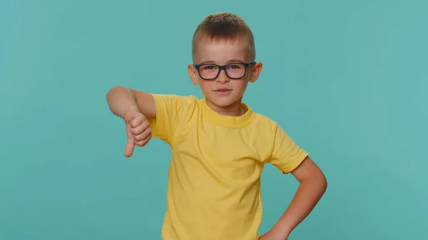 嫌いだ 親指をサインジェスチャーを示す動揺の小さな幼児の子供の少年は 不承認 不満を表現しています 若いです就学前の子供で眼鏡で一人でブルースタジオの背景に — ストック写真