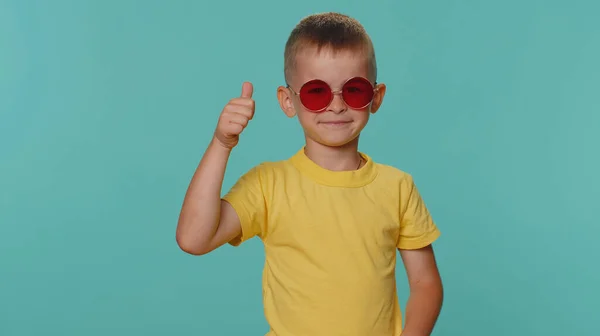 具有诱惑力的小孩穿着黄色T恤 戴着红色太阳镜 迷人的笑容 人的情感 戴眼镜的学龄前幼儿孤身一人 背景是蓝色的 — 图库照片