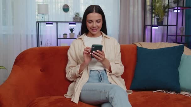 Portrait Adult Girl Sitting Sofa Uses Mobile Phone Smile Modern — Stockvideo