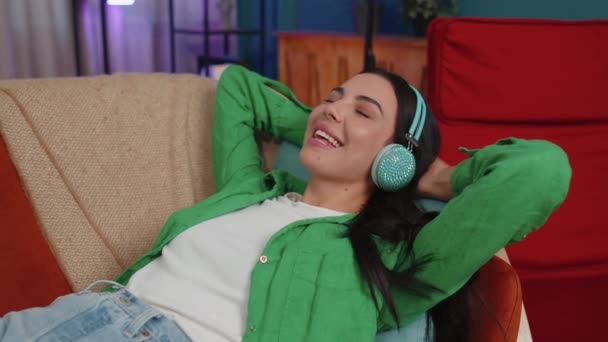 Young Woman Wireless Headphones Relaxing Lying Sofa Home Choosing Listening — Stock video