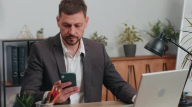 Businessman in suit working, having mobile phone talk at office workplace desk with laptop. Professional manager freelance man holding smartphone using messenger chat apps. Employment, occupation
