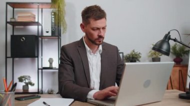 Businessman in suit working on laptop computer shakes finger and saying no, be careful, scolding and giving advice to avoid danger mistake, disapproval sign at office. Confident serious freelancer man