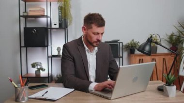 Like. Happy businessman in suit working on laptop looking approvingly at camera showing thumbs up, like sign positive something good, positive feedback at office workplace desk. Freelancer adult man