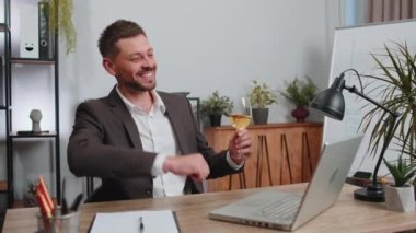 Businessman working on laptop celebrate successful contract agreement with colleague client at office workplace desk. Freelancer man drinking champagne. Online remote video call conversation job