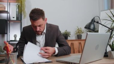 Businessman working on laptop analyzing financial graph decrease loses becoming surprised sudden results, bad news, fortune loss fail at office. Irritated angry freelancer man breaking pencil in hands