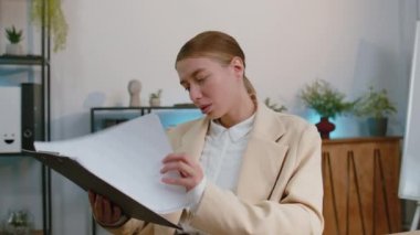Oh my God, Wow. Businesswoman in suit working analysing paperwork documents raising hands in surprise, shocked by sudden victory, good news at home office desk. Confident manager freelancer woman