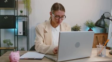 Happy business woman working on laptop computer sincerely rejoicing win, receiving money dollar cash banknotes, success lottery luck at office workplace desk. Professional manager freelancer girl