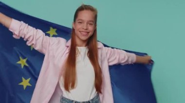 Lovely pretty teenager girl waving European Union flag, smiling, cheering democratic laws, human rights, freedoms in Europe. Young female child kid isolated alone on blue studio background indoors
