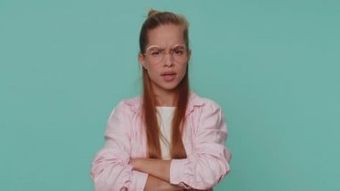 Offended pretty teenager girl having misunderstanding, frustrated after quarrel, ignores and does not want to communicate, talk. Young female child kid isolated on blue studio background indoors