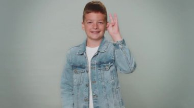 Countdown to holiday birthday celebration. Portrait of cheerful toddler kid boy winner counting in reverse order from five to one, lottery jackpot. Young teenager child schoolboy on gray background