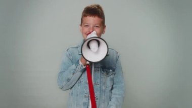 Smiling happy toddler boy talking with megaphone, proclaiming news, loudly announcing sale advertisement, warning using loudspeaker to shout speech. Young teenager children. Child on gray background