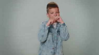 Aggressive toddler kid boy making fight threat at camera, shaking fist punch, boxing with expression, punishment, practicing exercises, negative rage. Young teenager child schoolboy on gray background