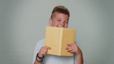Toddler young boy reading funny interesting fairytale story book, leisure hobby, knowledge wisdom, education, learning, study, wow. School children teenager child isolated on gray studio background