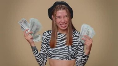 Lovely pretty young woman holding fan of cash money dollar banknotes celebrate dance, success business career, lottery game winner, big income, wealth. Adult stylish girl on beige studio background
