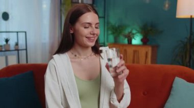 Portrait of thirsty lovely girl sitting indoors holding glass of natural aqua make sips drinking still water preventing dehydration. Woman with good life habits, healthy slimming, weight loss concept