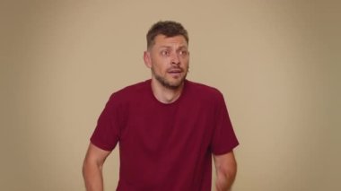 Scared fearful young man covering ears with hands, closing eyes, meeting own phobia, evidence horror event, screaming, shouting at loud, freaked out. Adult stylish guy on beige studio background