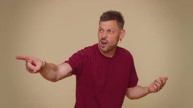 Get out of here. You are fired. Dissatisfied young man pointing finger away asking to leave his alone, strict boss firing, conflict, crisis, deadline. Adult stylish guy on beige studio wall background