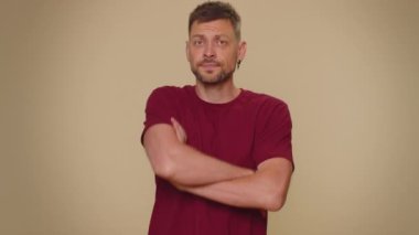 Offended handsome young man having misunderstanding, frustrated after quarrel, ignores and does not want to communicate, talk. Adult stylish male guy isolated on beige studio background indoors