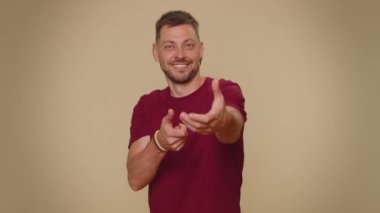 Bearded handsome young man mime pulling an imaginary unreal invisible rope, puts lot of effort into showing how enduring, strong she is. Adult stylish male guy isolated on beige studio wall background