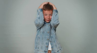 Stresli küçük çocuk 10 yaşında korkusunu ifade ediyor ve ellerini tehlikeden uzaklaştırıyor, hayır diyor. Korkak çocuklar. Genç çocuk. Gri stüdyo arka planında yalnız başına.