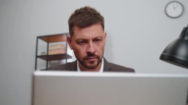 Close-up portrait face businessman freelancer in suit at office workplace, working on laptop computer. Manager freelancer man works on notebook, sends messages makes online purchases watching movies