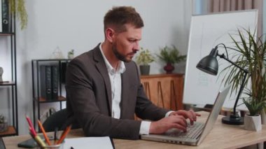 Dislike. Upset businessman in suit working on laptop computer at home office thumbs down sign gesture, expressing discontent, disapproval, dissatisfied bad work. Displeased serious male freelancer man