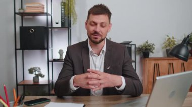 Video screen view of businessman working on laptop computer at home office desk talk on online communication video call with employee, boss. Manager man freelancer support services looking at camera