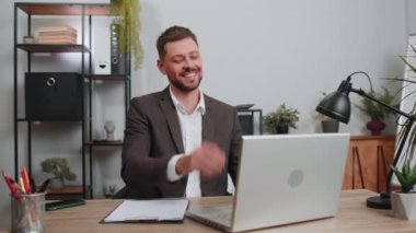 Cheerful rich businessman in suit working on laptop and wasting throwing money to camera, more tips earnings, big profit, success win lottery, shopping. Happy male freelancer man at home office desk