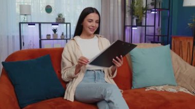 Happy girl businesswoman freelancer work with documents from home, analyzing information, read business papers prepare financial report. Young woman winner shocked by sudden victory, good success news