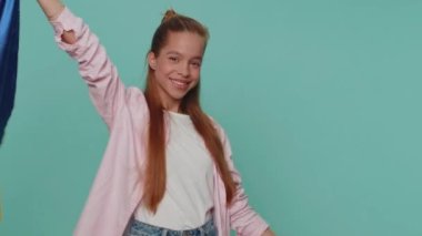 Teenager girl hold Ukraine national flag, showing victory sign against war, hoping for success and win doing peace gesture smiling with kind optimistic expression. Student child kid on blue background