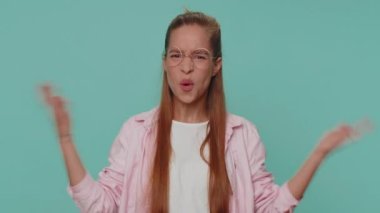 Pretty teenager girl raising hands in indignant expression, asking why, what reason of failure, demonstrating disbelief irritation by troubles. Young teen child kid isolated on blue studio background