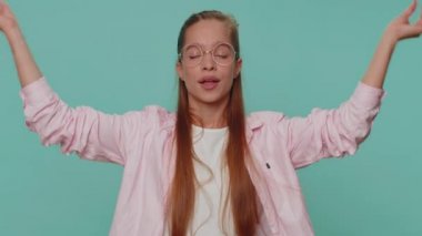 Keep calm down, relax, inner balance. Teenager young girl breathes deeply with mudra gesture, eyes closed, meditating with concentrated thoughts, peaceful mind. Student child kid on blue background