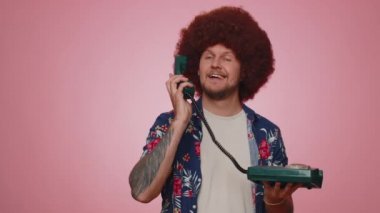 Hey sen, beni ara. Mavi gömlekli neşeli sekreter 80 'lerin telli vintage telefonundan konuşuyor. Beni geri ara diyor. Pembe stüdyo duvarında izole bir şekilde poz veren genç adam.
