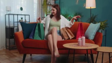 Portrait of caucasian adult girl happy shopaholic consumer came back home after shopping sale with bags. Young woman satisfied received parcels from online order at modern home apartment living room