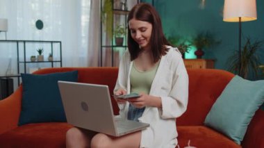 Planning budget. Rich happy young woman counting money cash use laptop computer calculate domestic bills at home. Joyful adult girl satisfied of income earnings, saves money for planned vacation gifts